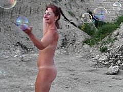 Μια γυμνή ώριμη γυναίκα διασκεδάζει με σαπουνόφουσκες